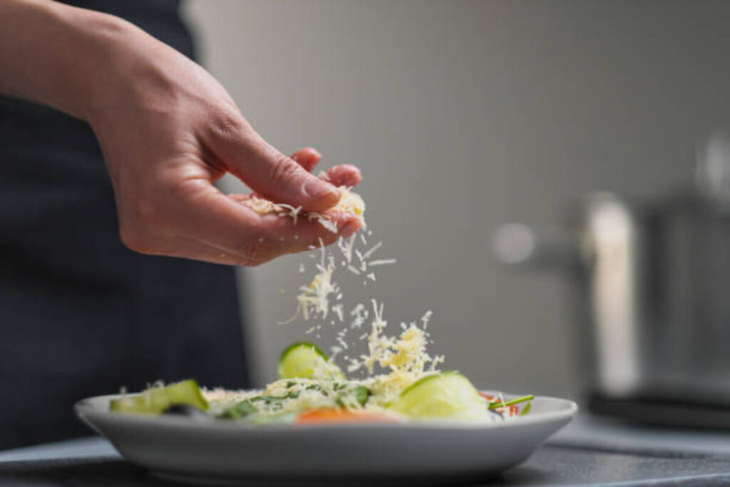 a female chef in a white uniform and a black apron in the restaurant kitchen cooking the cook